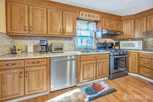 kitchen featuring decorative backsplash, sink, light wood-type flooring, stainless steel dishwasher, and black range with gas stovetop