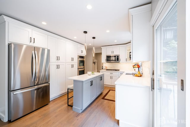 5 Wedgewood Ln, Holmdel, NJ 07733 - kitchen with appliances with stainless steel finishes, a kitchen island, light wood finished floors, white cabinetry, and light countertops