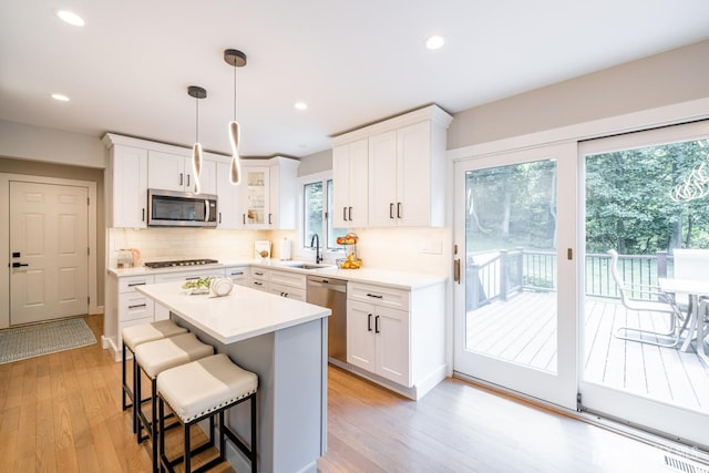 5 Wedgewood Ln, Holmdel, NJ 07733 - kitchen with appliances with stainless steel finishes, light wood-style flooring, decorative backsplash, a breakfast bar, and a kitchen island
