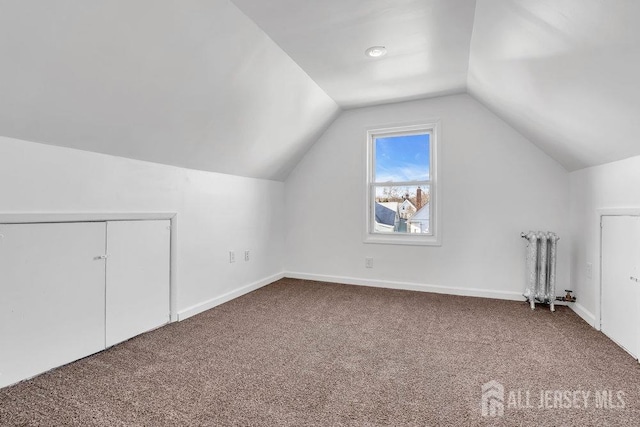 bonus room with radiator heating unit, carpet, and lofted ceiling