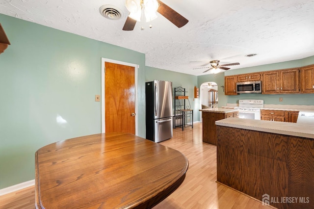 109 Russell St, Woodbridge Proper, NJ 07095 - kitchen with appliances with stainless steel finishes, ceiling fan, light countertops, arched walkways, and light wood-type flooring