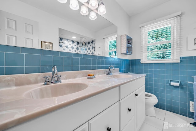 10 Margie Rd, East Brunswick, NJ 08816 - bathroom featuring tile walls, toilet, double vanity, tile patterned floors, and wainscoting