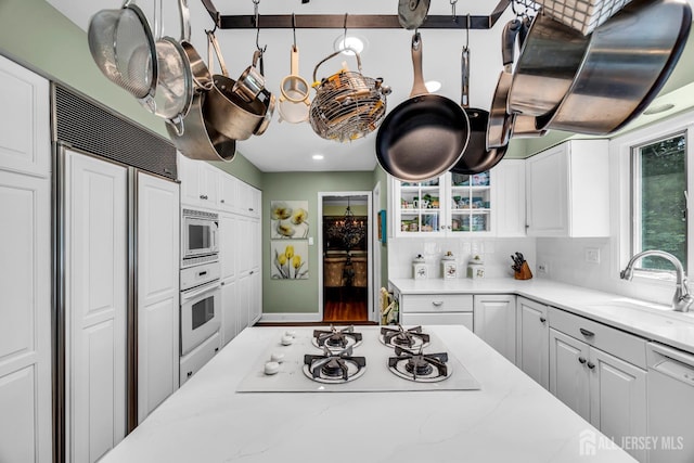 10 Margie Rd, East Brunswick, NJ 08816 - kitchen featuring built in appliances, a sink, white cabinets, light stone counters, and backsplash