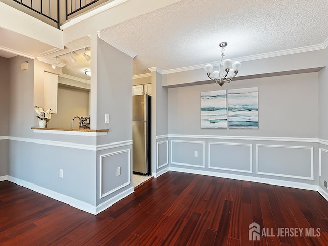 1010 Aspen Dr, Plainsboro, NJ 08536 - unfurnished dining area with dark wood-style flooring, a chandelier, wainscoting, a textured ceiling, and crown molding