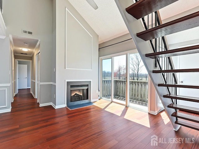 1010 Aspen Dr, Plainsboro, NJ 08536 - unfurnished living room with stairs, wood finished floors, a warm lit fireplace, baseboards, and a towering ceiling