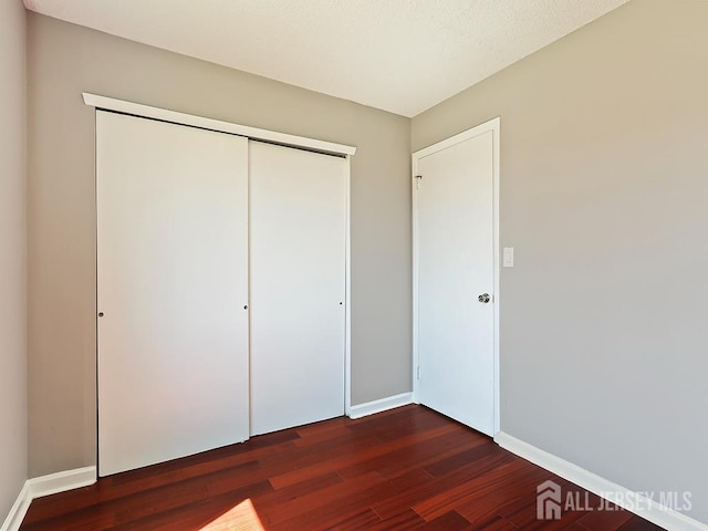 1010 Aspen Dr, Plainsboro, NJ 08536 - unfurnished bedroom featuring dark wood-type flooring, baseboards, and a closet