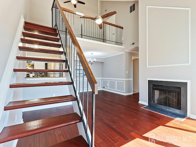 1010 Aspen Dr, Plainsboro, NJ 08536 - stairway featuring a towering ceiling, ceiling fan, wood finished floors, a fireplace with flush hearth, and a wainscoted wall