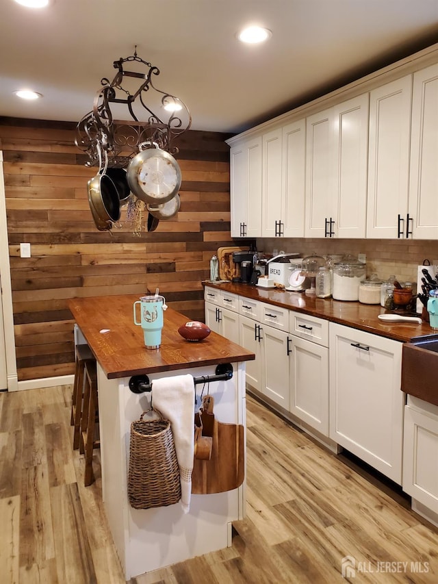 kitchen featuring a breakfast bar, wood counters, light wood-style floors, white cabinets, and a center island