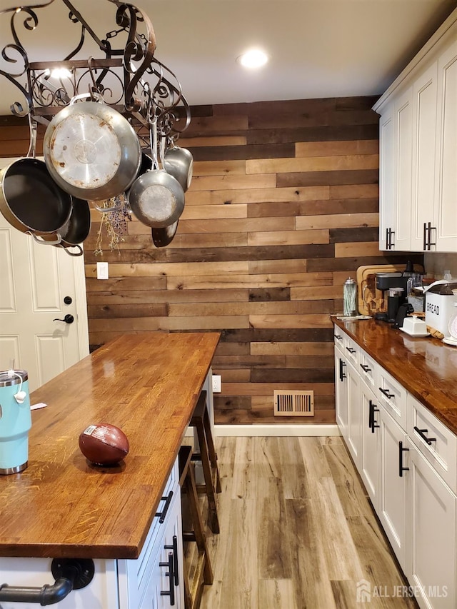 kitchen featuring wood walls, wood counters, visible vents, and white cabinets