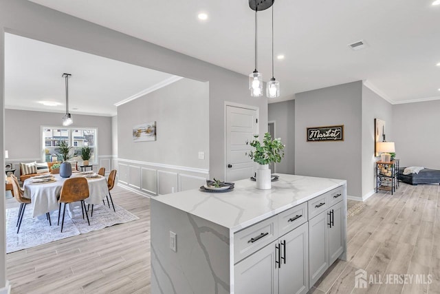 28 Kenmore Rd, Edison, NJ 08817 - kitchen featuring crown molding, light wood-style flooring, light stone countertops, hanging light fixtures, and a center island