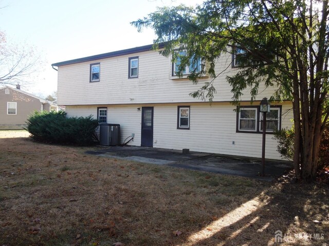 rear view of house featuring a yard, central AC unit, and a patio area