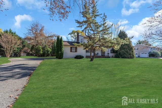 view of front of property with gravel driveway and a front lawn