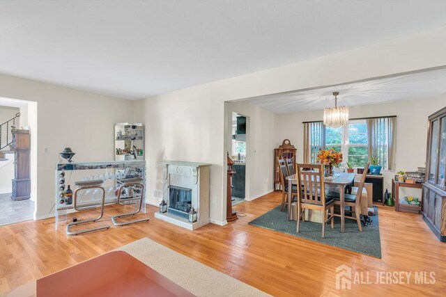 dining space featuring a chandelier, stairs, a multi sided fireplace, and wood finished floors