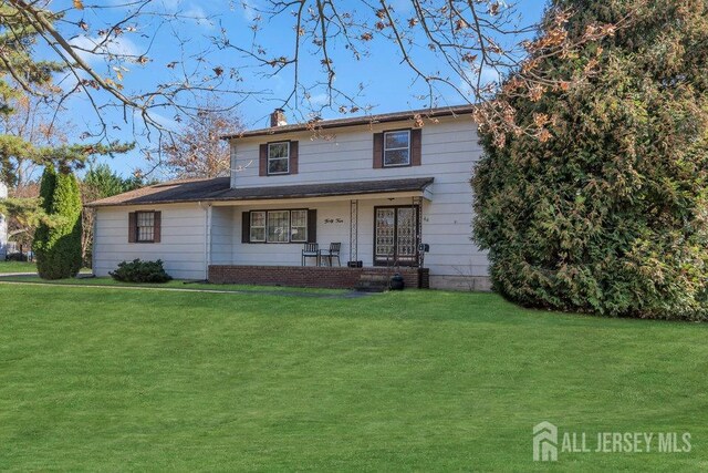 traditional home with covered porch, a front lawn, and a chimney