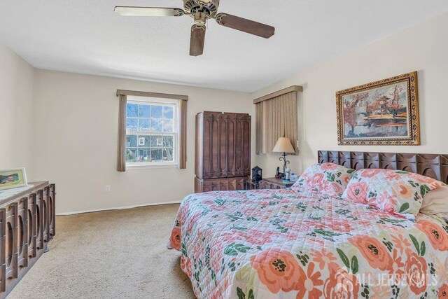 carpeted bedroom with ceiling fan and baseboards