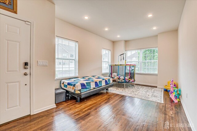 bedroom with wood finished floors, baseboards, and recessed lighting