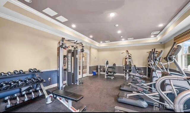 workout area featuring a tray ceiling, ornamental molding, baseboards, and recessed lighting
