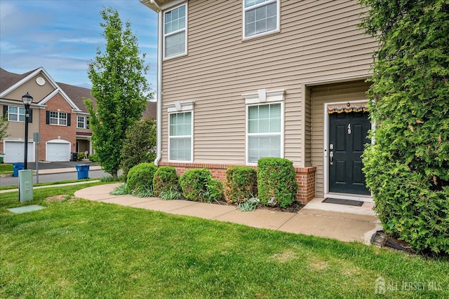 entrance to property featuring a yard and brick siding