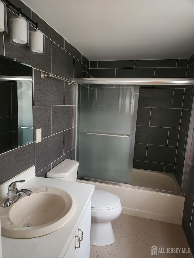 53 Suydam St, New Brunswick, NJ 08901 - full bath with tile patterned flooring, toilet, vanity, tile walls, and combined bath / shower with glass door