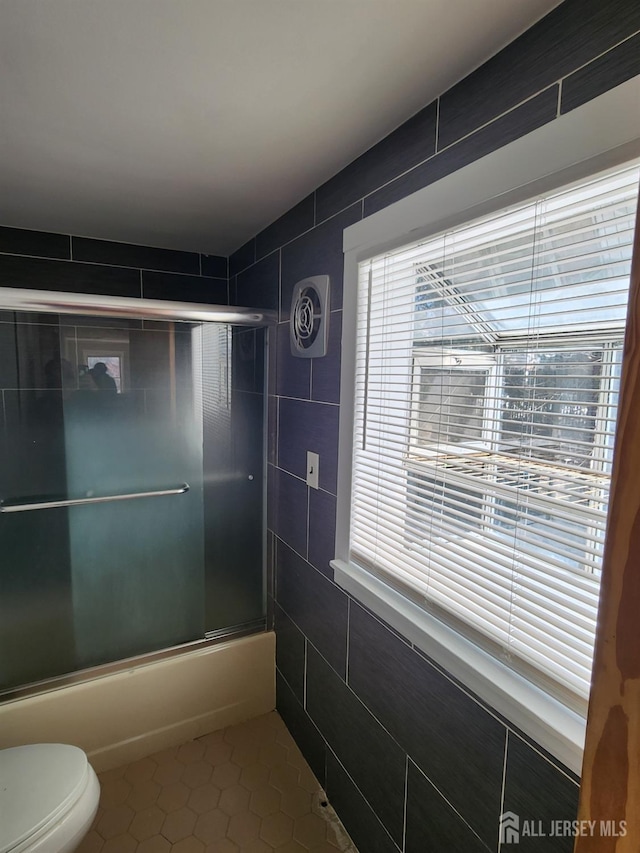 53 Suydam St, New Brunswick, NJ 08901 - bathroom with tile patterned floors, toilet, bath / shower combo with glass door, tile walls, and plenty of natural light