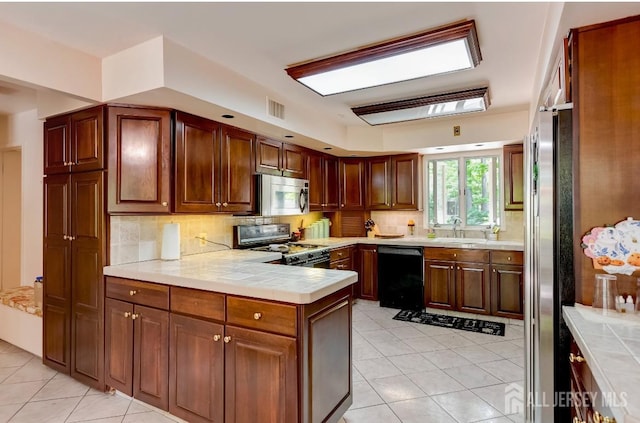 kitchen with light tile patterned flooring, sink, decorative backsplash, kitchen peninsula, and black appliances