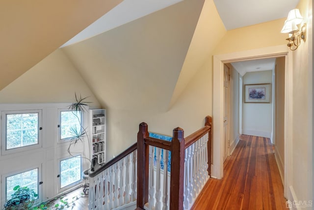 hallway with lofted ceiling, a healthy amount of sunlight, and hardwood / wood-style floors