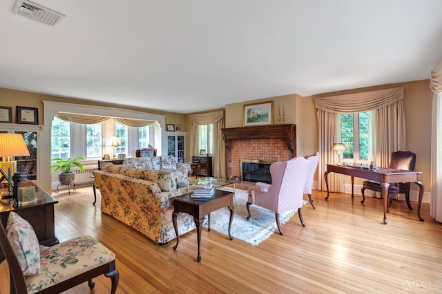 living room featuring a fireplace, a wealth of natural light, and light hardwood / wood-style floors