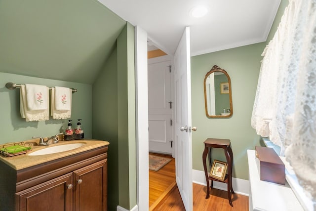 bathroom featuring crown molding, vanity, vaulted ceiling, and hardwood / wood-style flooring