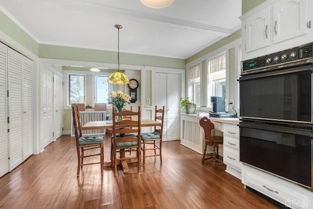 dining space featuring dark wood-type flooring, crown molding, and a healthy amount of sunlight