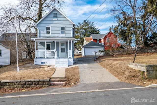 front facade featuring covered porch, a garage, and an outbuilding