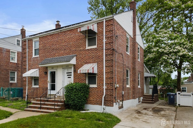 678 Bingle St, Perth Amboy, NJ 08861 - view of front facade featuring a chimney, entry steps, brick siding, and concrete driveway