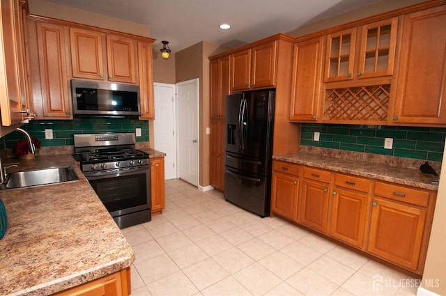 kitchen featuring light stone counters, appliances with stainless steel finishes, sink, and backsplash