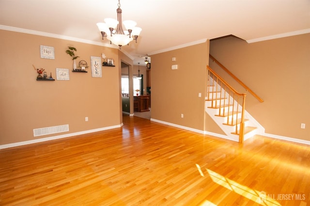 unfurnished room featuring hardwood / wood-style flooring, ornamental molding, and a notable chandelier