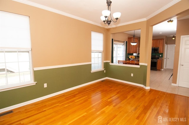 spare room featuring crown molding, a chandelier, and light wood-type flooring