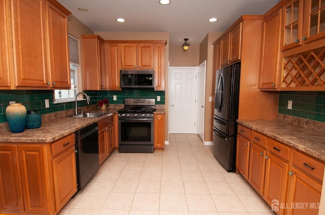 kitchen featuring sink, decorative backsplash, light tile patterned floors, light stone counters, and black appliances