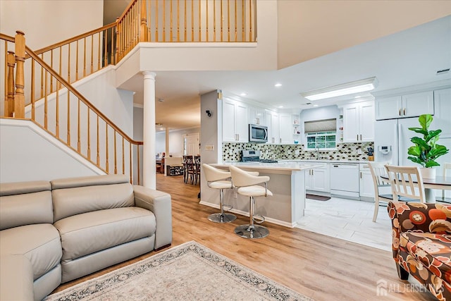 7 Cambridge Ct, East Brunswick, NJ 08816 - living room with light wood-type flooring, stairs, a high ceiling, ornate columns, and recessed lighting