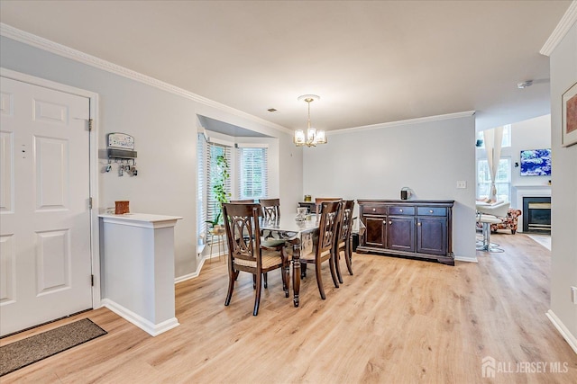 7 Cambridge Ct, East Brunswick, NJ 08816 - dining space with light wood finished floors, a chandelier, healthy amount of natural light, ornamental molding, and a glass covered fireplace