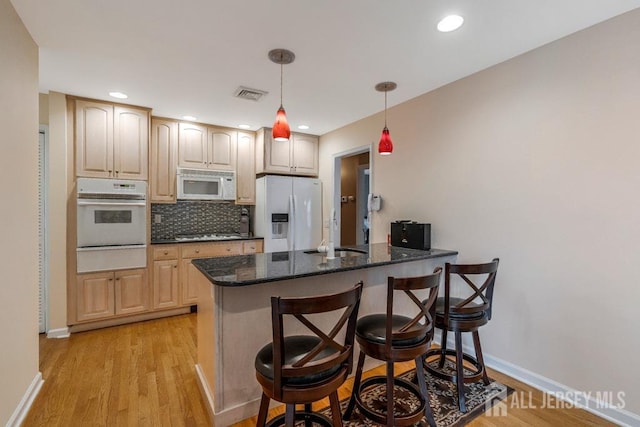 kitchen featuring a warming drawer, visible vents, white appliances, a peninsula, and decorative backsplash