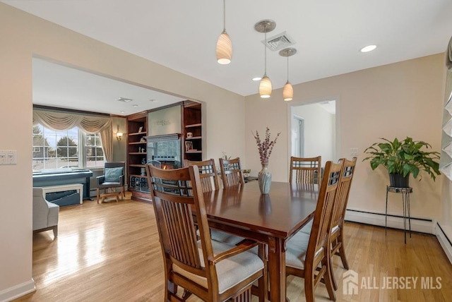 dining space with a baseboard heating unit, light wood-style flooring, recessed lighting, and visible vents