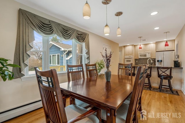 dining area with a wealth of natural light, light wood-style flooring, and a baseboard radiator