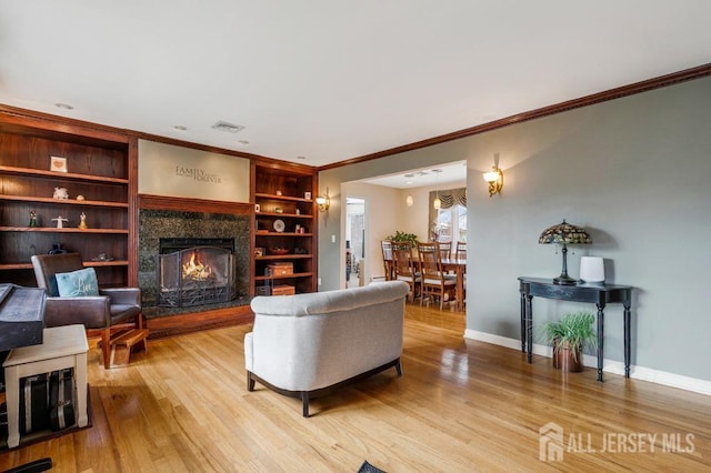 living area with light wood-type flooring, baseboards, visible vents, and a warm lit fireplace