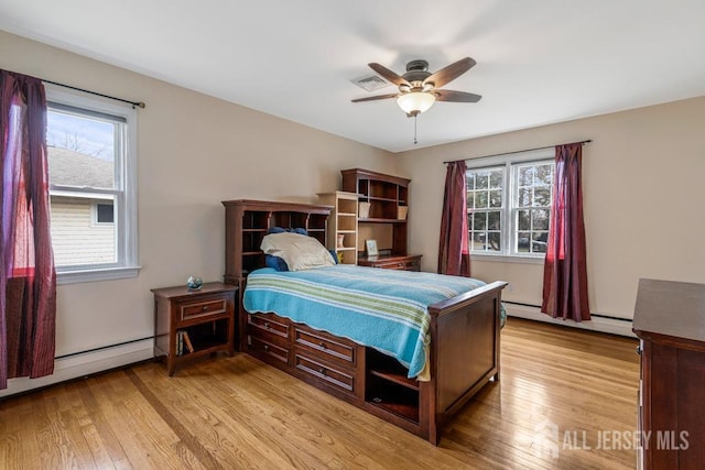 bedroom with a baseboard heating unit, multiple windows, light wood-style floors, and a ceiling fan