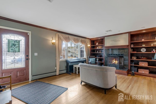 living room featuring a baseboard heating unit, a lit fireplace, wood finished floors, and ornamental molding