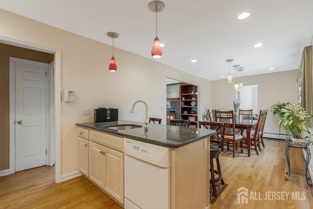 kitchen with light brown cabinets, a peninsula, a sink, dishwasher, and light wood-type flooring