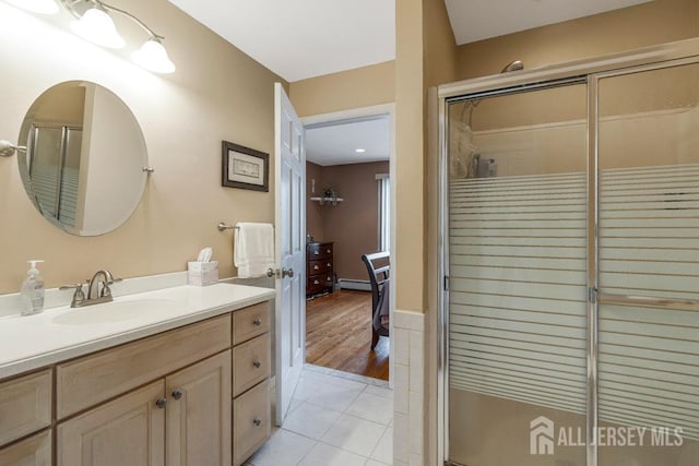 bathroom with tile patterned floors, a baseboard heating unit, a stall shower, and vanity