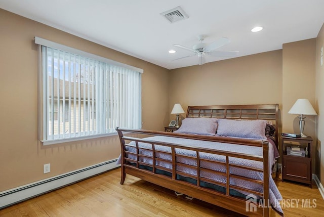 bedroom with visible vents, recessed lighting, a baseboard heating unit, and wood finished floors