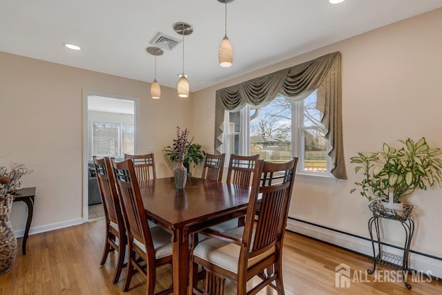 dining space with visible vents, baseboards, baseboard heating, and light wood-style flooring