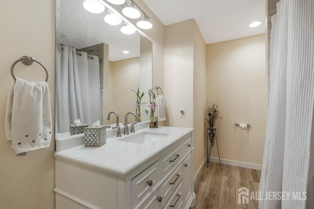 full bathroom featuring curtained shower, baseboards, recessed lighting, wood finished floors, and vanity