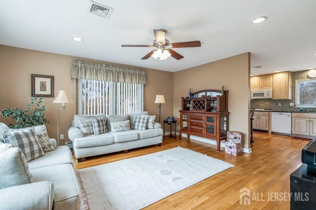 living room featuring visible vents, ceiling fan, light wood-type flooring, baseboard heating, and recessed lighting