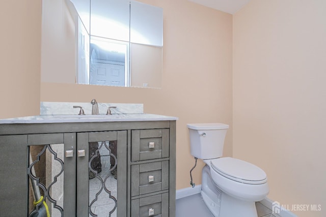 half bathroom featuring toilet, baseboards, vanity, and tile patterned flooring